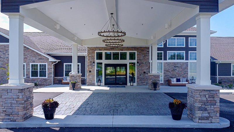 Covered main entrance at Charter Senior Living of Paducah, KY, featuring stone columns, stylish lighting, and easy access for residents and guests.