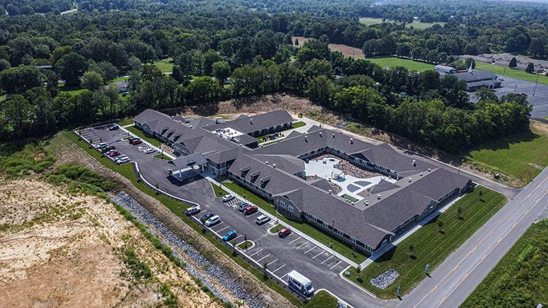 Aerial view of Charter Senior Living of Paducah, KY, showing the full campus layout, landscaped courtyard, and ample parking surrounded by greenery.