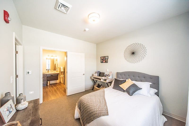 Private bedroom at Charter Senior Living of Paducah, KY, featuring a cozy bed, bright decor, and an en-suite bathroom for comfort and convenience.