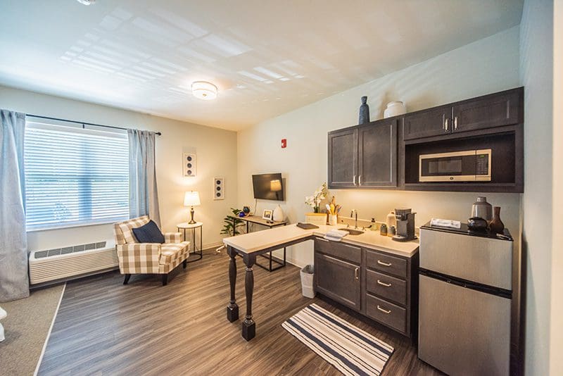 Comfortable senior apartment at Charter Senior Living of Paducah, KY, featuring a cozy sitting area, kitchenette with modern appliances, and natural lighting.
