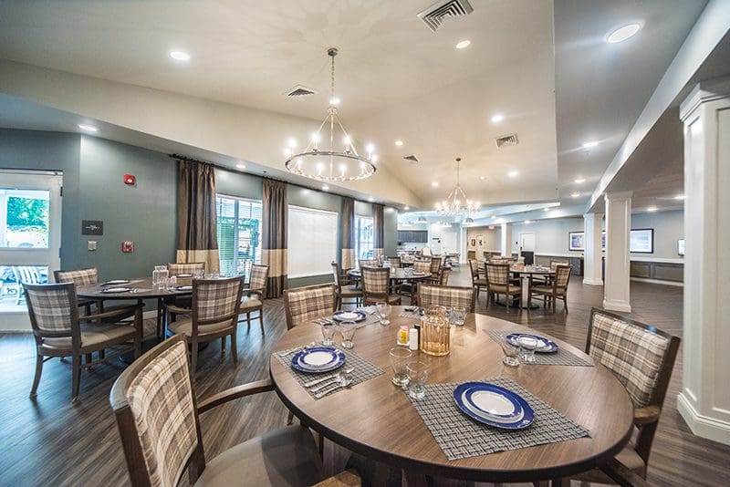 Bright, elegant dining room with round tables set for a meal at Charter Senior Living of Paducah.