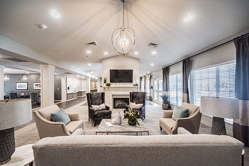 Inviting lounge area at Charter Senior Living of Paducah, KY, featuring cozy seating, a fireplace, and natural lighting—ideal for resident relaxation and social gatherings.